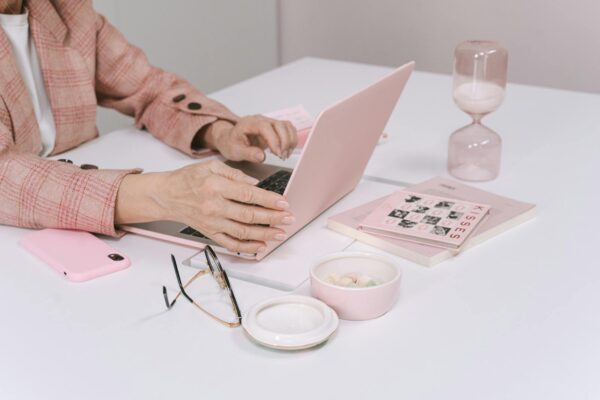 A woman uses a laptop surrounded by pink office accessories, creating a stylish workspace.
